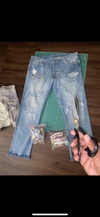 a person cutting a pair of jeans with scissors